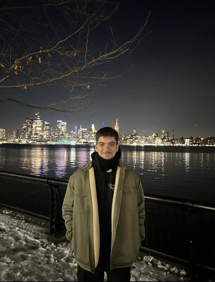 Mehmet Bisen by the Hudson River at night, Manhattan skyline behind him
